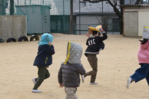 子供たちが防災頭巾のかぶり教室から校庭に避難訓練をする姿です。