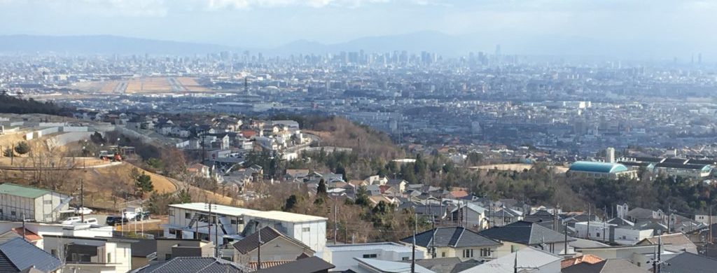 山手台の高台から見下ろした風景で、右側には学校、左側には空港など、眼下に街の風景が広がっている。